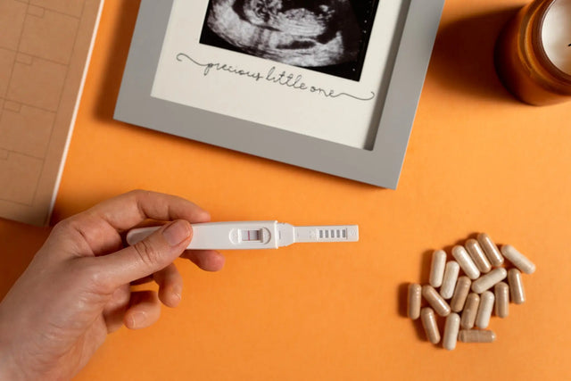 a pregnancy detection kit with a sonogram and some supplements lying on the table